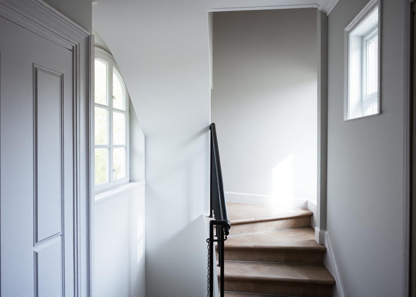 Nymålat trapphus i ljusgrått med svart smidesräcke